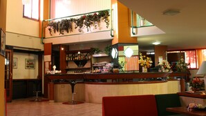 Un vestíbulo de hotel con mostrador de recepción, zona de estar y una escalera que conduce a un nivel superior.