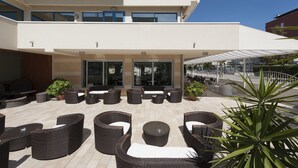 A modern outdoor seating area with wicker furniture and potted plants. - Hotel Miami (Jesolo)