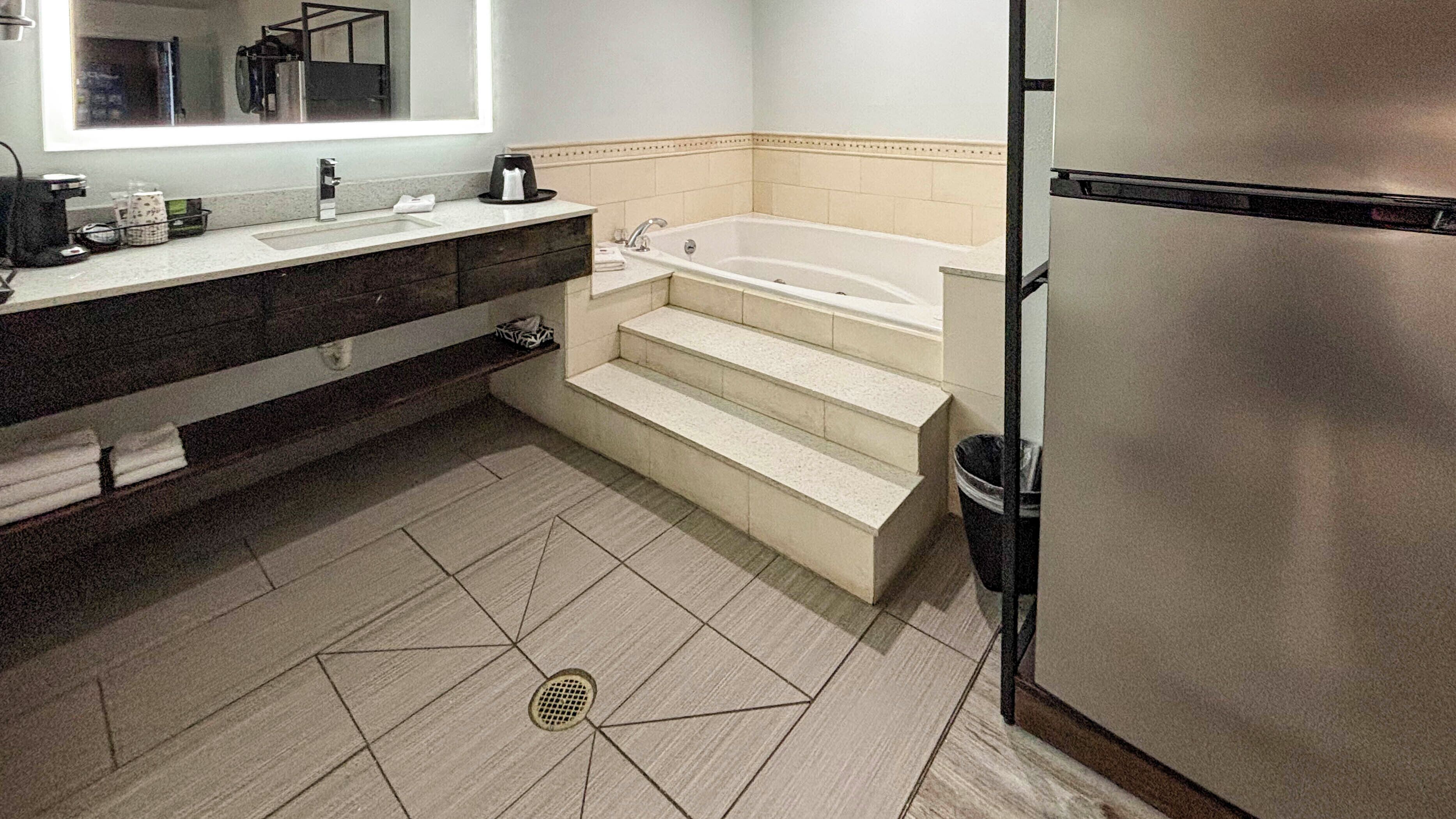 A modern bathroom with a bathtub, a sink, and a refrigerator.