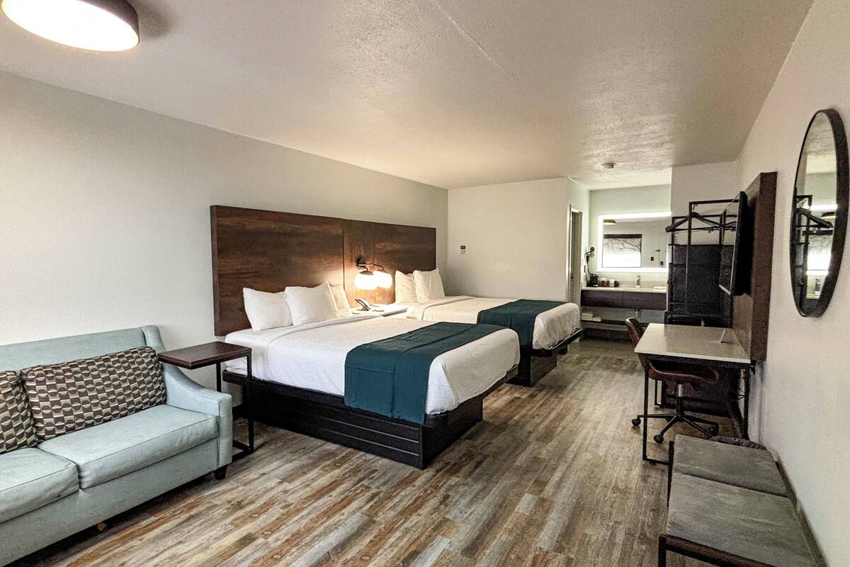 Ett hotellrum med två sängar, en soffa, ett skrivbord och en spegel.