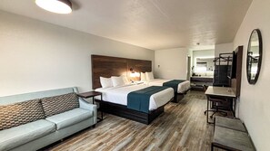 A hotel room with two beds, a sofa, a desk, and a mirror.