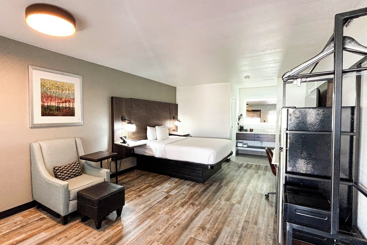 Ett hotellrum med en säng, en stol, ett skrivbord och en garderob.
