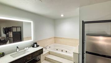 A bathroom with a large mirror, a bathtub, a sink, and a refrigerator.