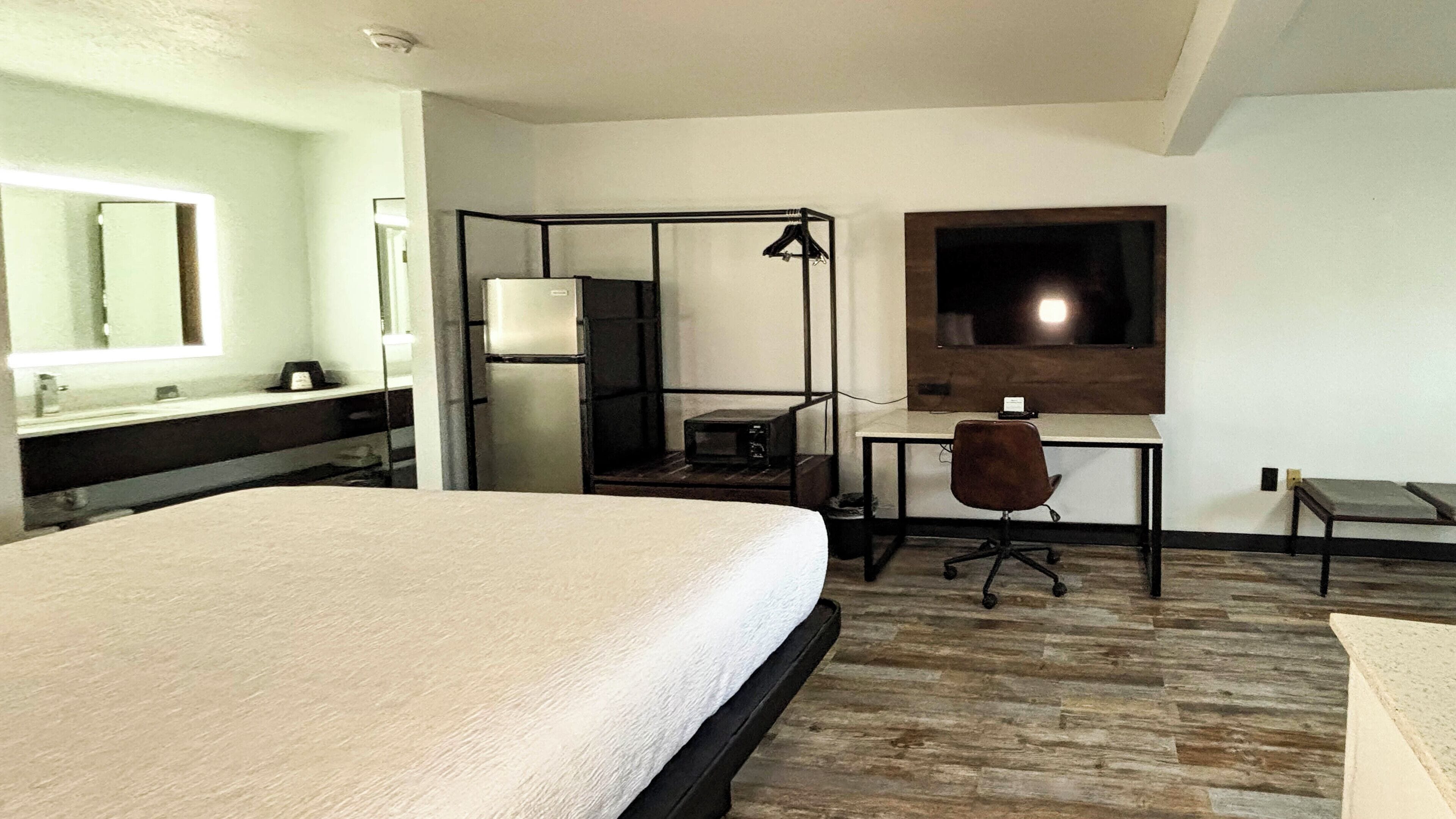 Une chambre d’hôtel avec un grand lit, un bureau avec une chaise, un téléviseur fixé au mur et une fenêtre.
