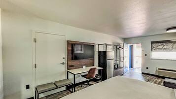 A hotel room with a bed, a desk, a chair, a TV, and a wardrobe.
