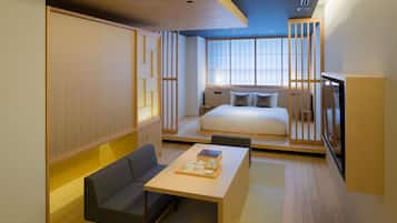 A compact hotel room with a bed, a sofa, a small table with a tray, and a TV.