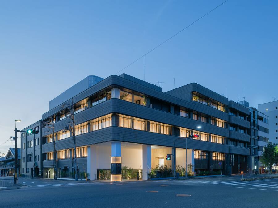 A modern multi-story hotel with a flat roof, large windows, and a well-lit entrance.