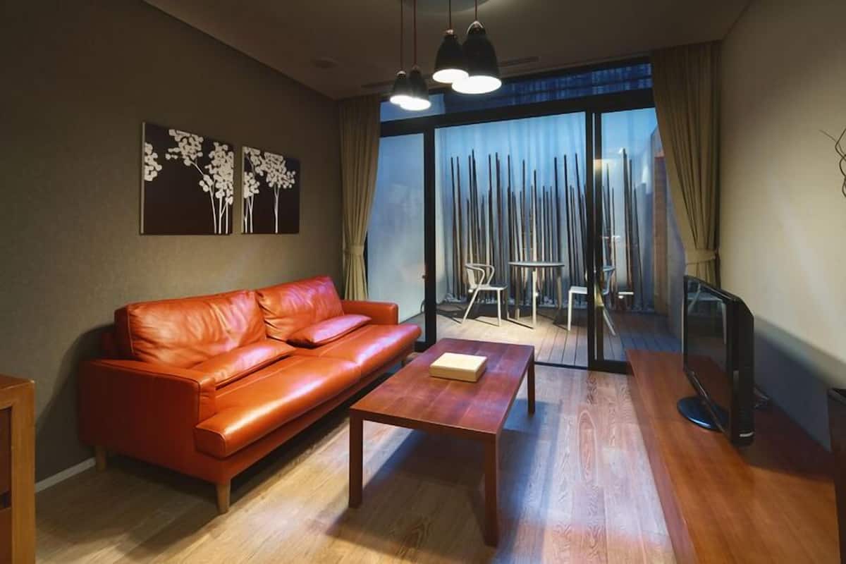 Un salon moderne avec un canapé en cuir, une table basse en bois et des œuvres d’art abstraites accrochées au mur.