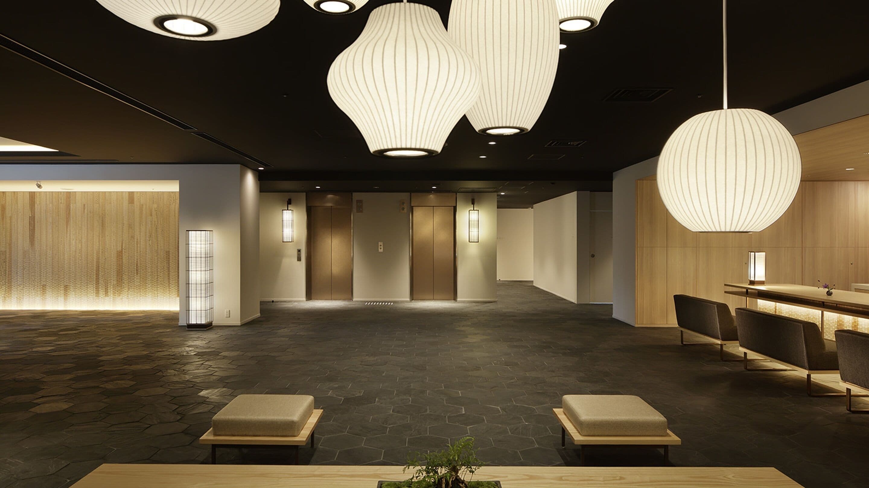 A modern lobby with a reception desk, seating area, and elevators.