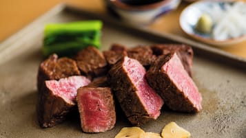 Un plato de carne de res en rodajas con verduras y salsas.