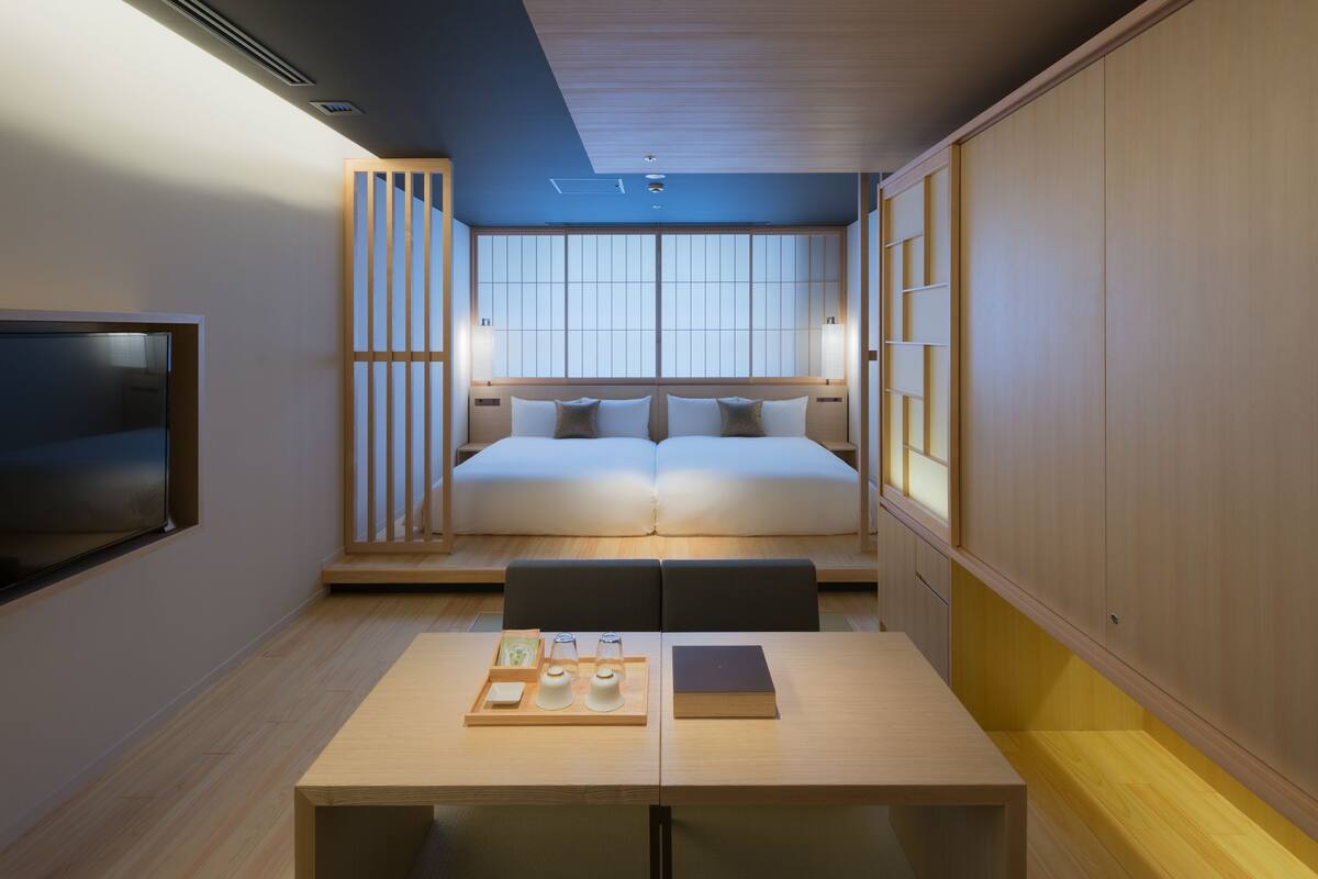 Un dormitorio con una cama, mesitas de noche y una televisión.