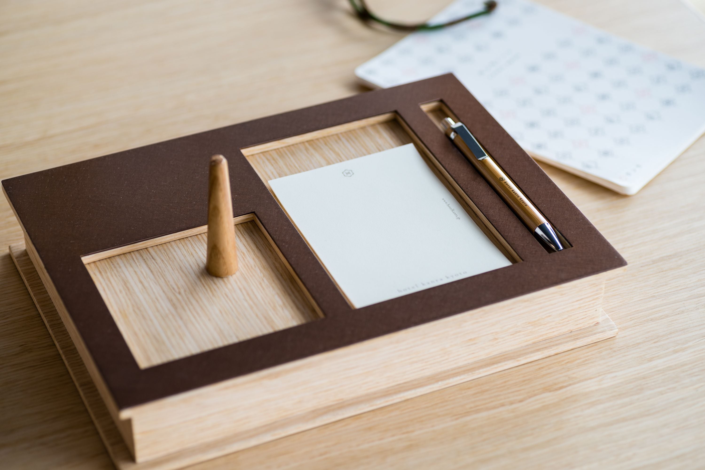 A wooden desk with a framed picture, a pen, and a calendar.