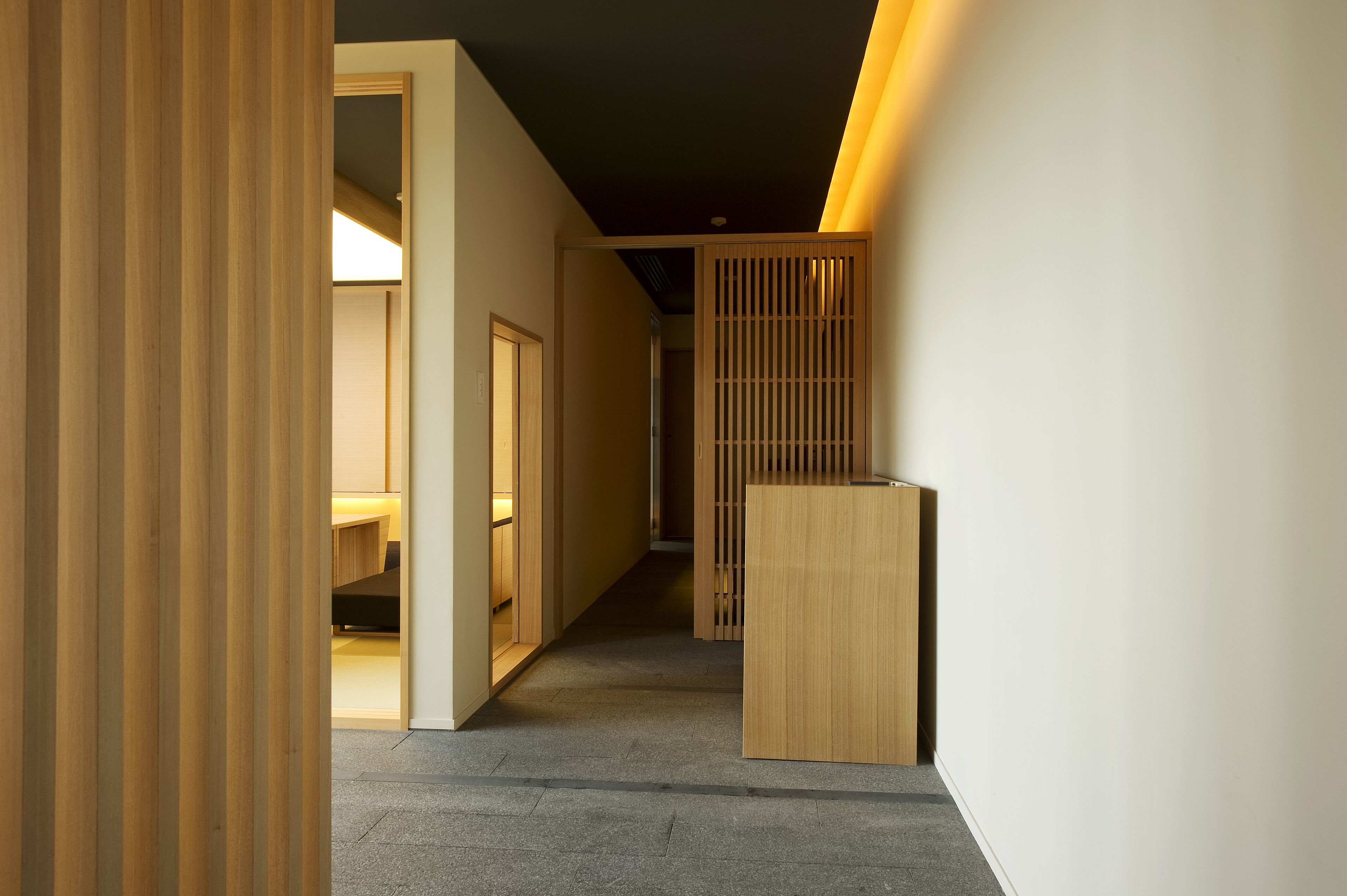 A hallway with wooden paneling, a reception desk, and a door leading to a room.