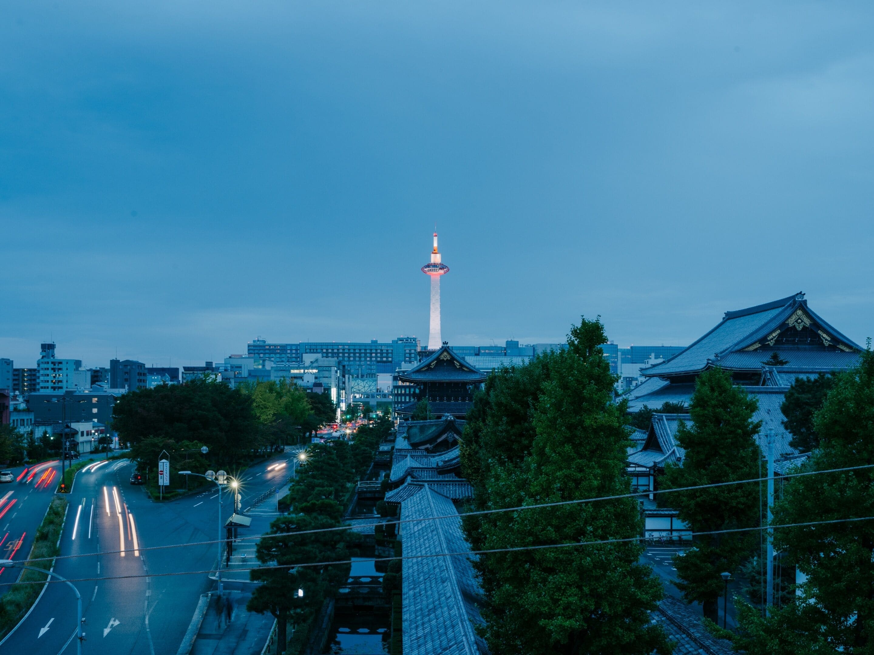 A cityscape with traditional architecture, a prominent tower, and a busy street.