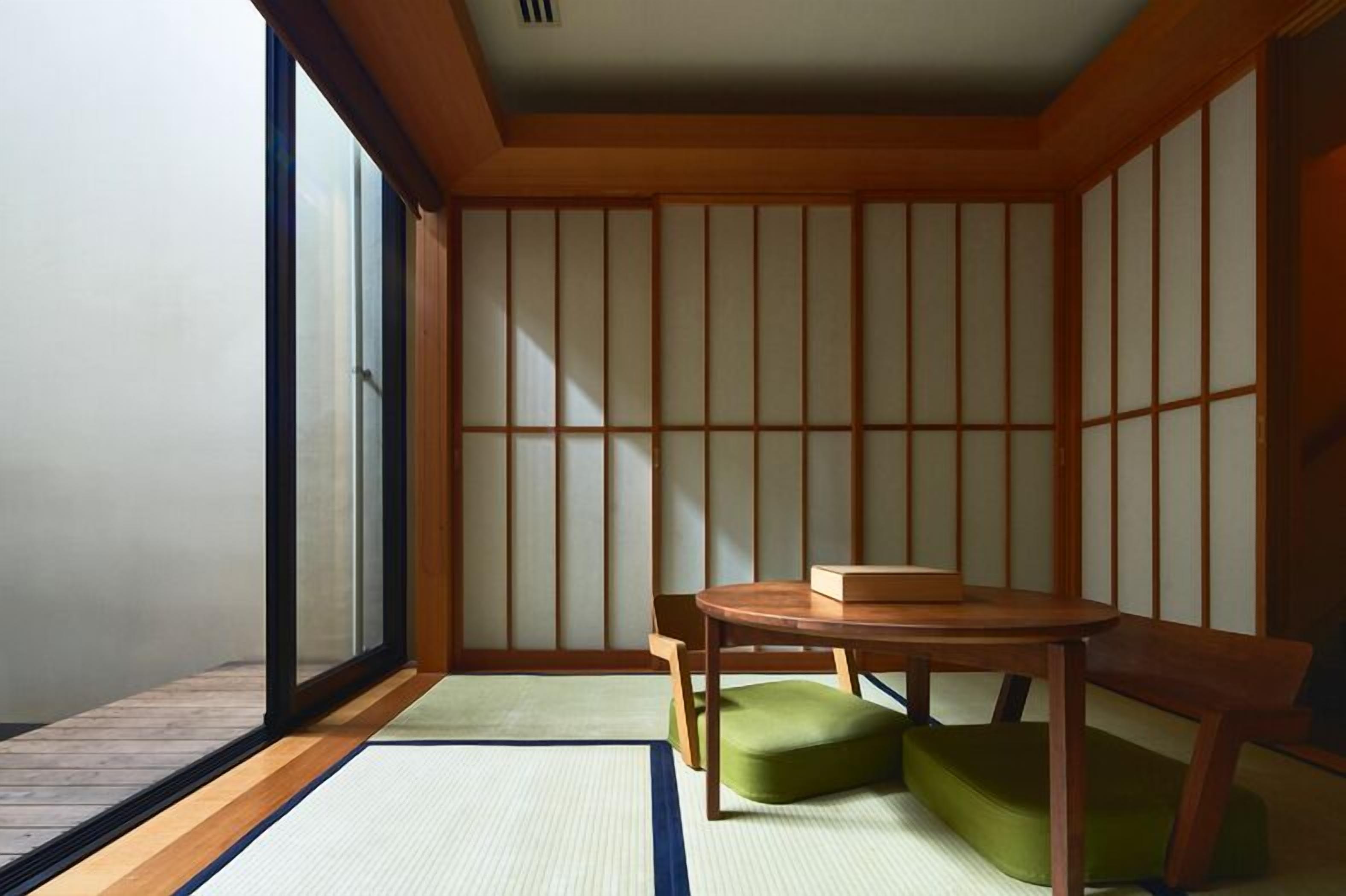 A traditional Japanese room with tatami flooring, a sliding door, and a small table with a cushion.
