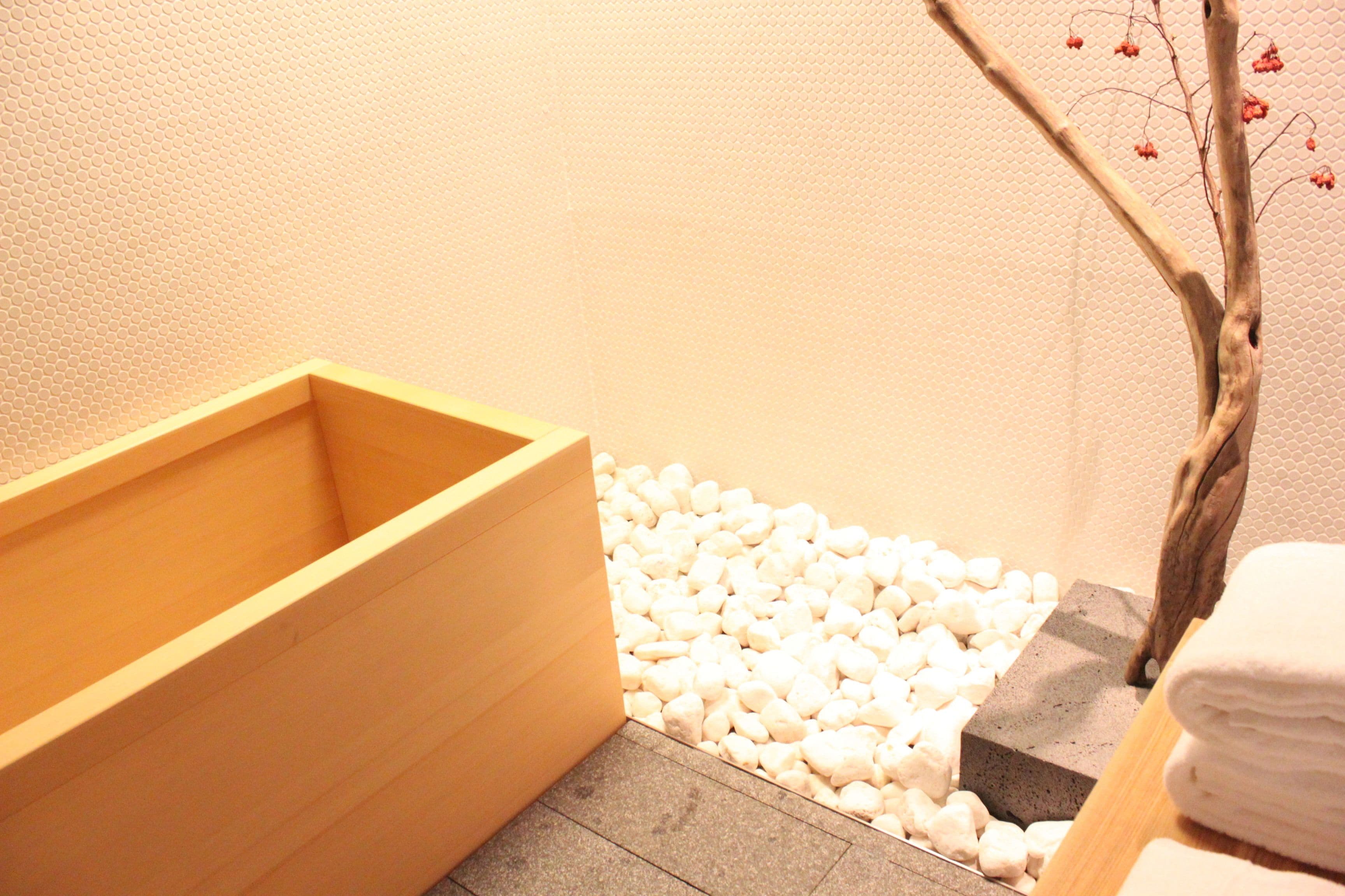 A wooden bathtub, white pebbles, and a tree branch with red berries.