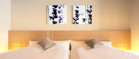 A double bed with two pillows, a wooden headboard, and two wall-mounted light fixtures.