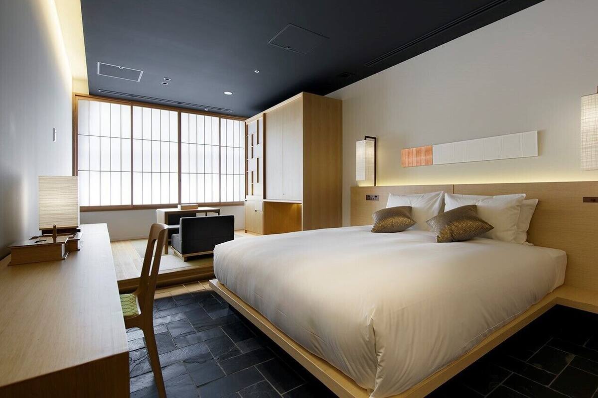 Una habitación de hotel moderna con cama, mesitas de noche, escritorio y ventana.