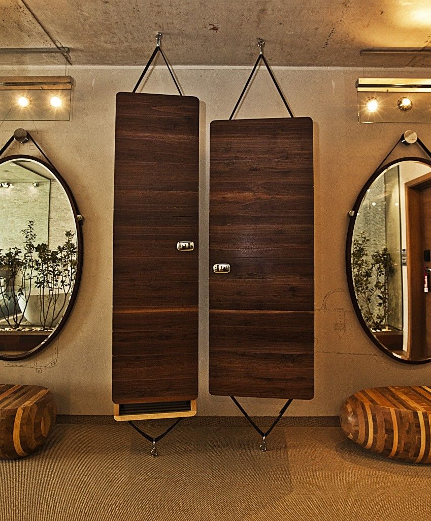 A room with two vertical wooden panels, a round mirror, and a wooden stool.