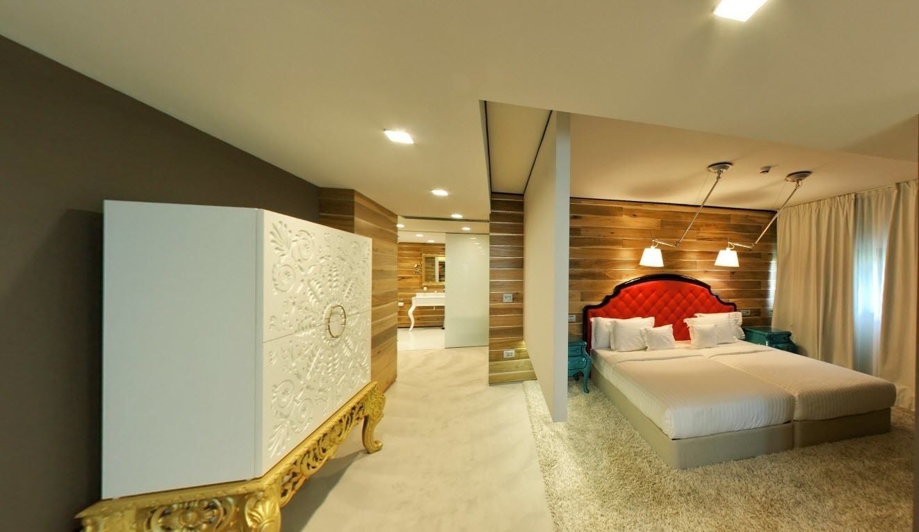 Una habitación de hotel con una cama grande, un armario y un baño al fondo.