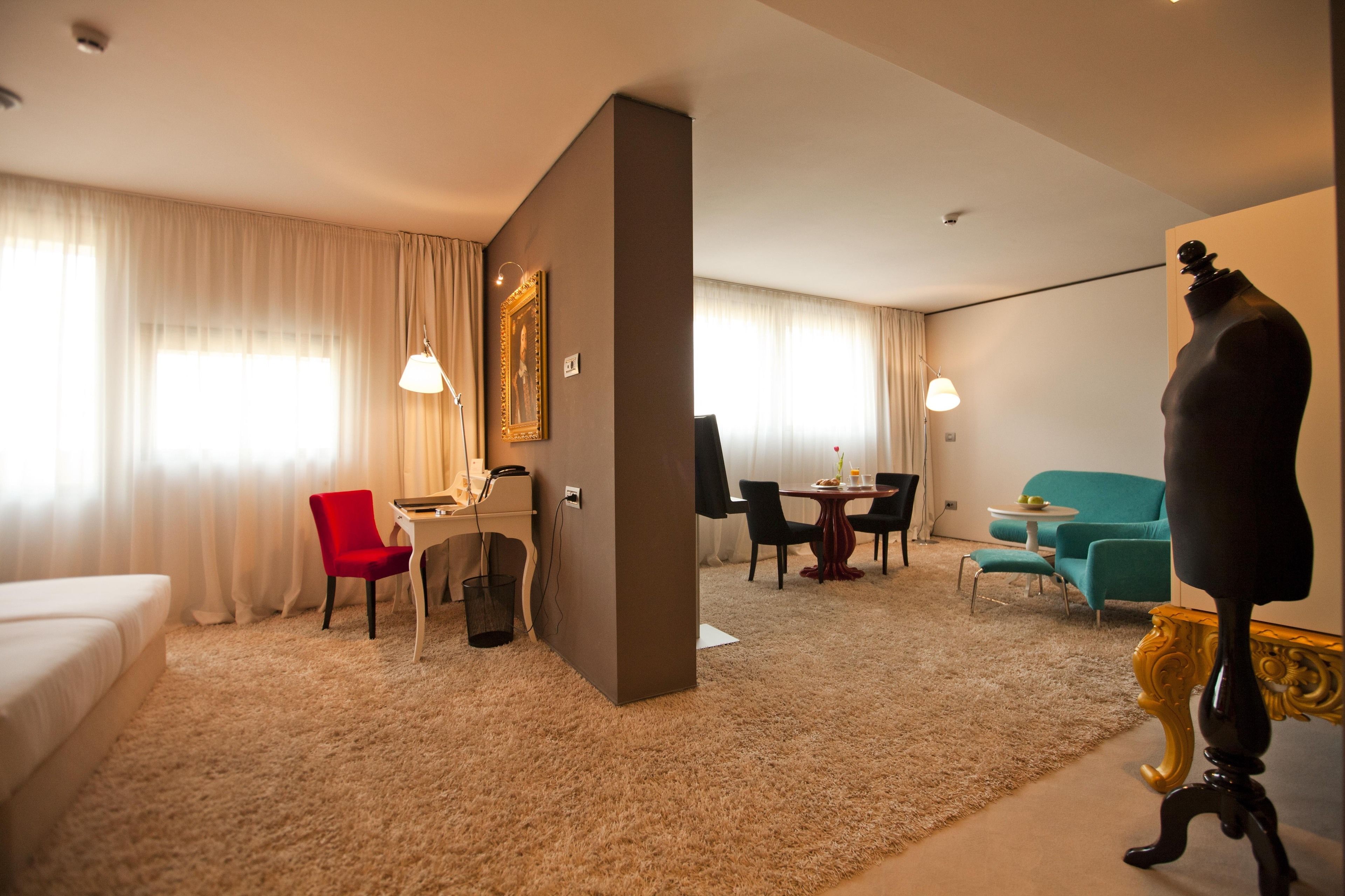 A hotel room with a bed, a desk, a chair, a dining table, and a mannequin.