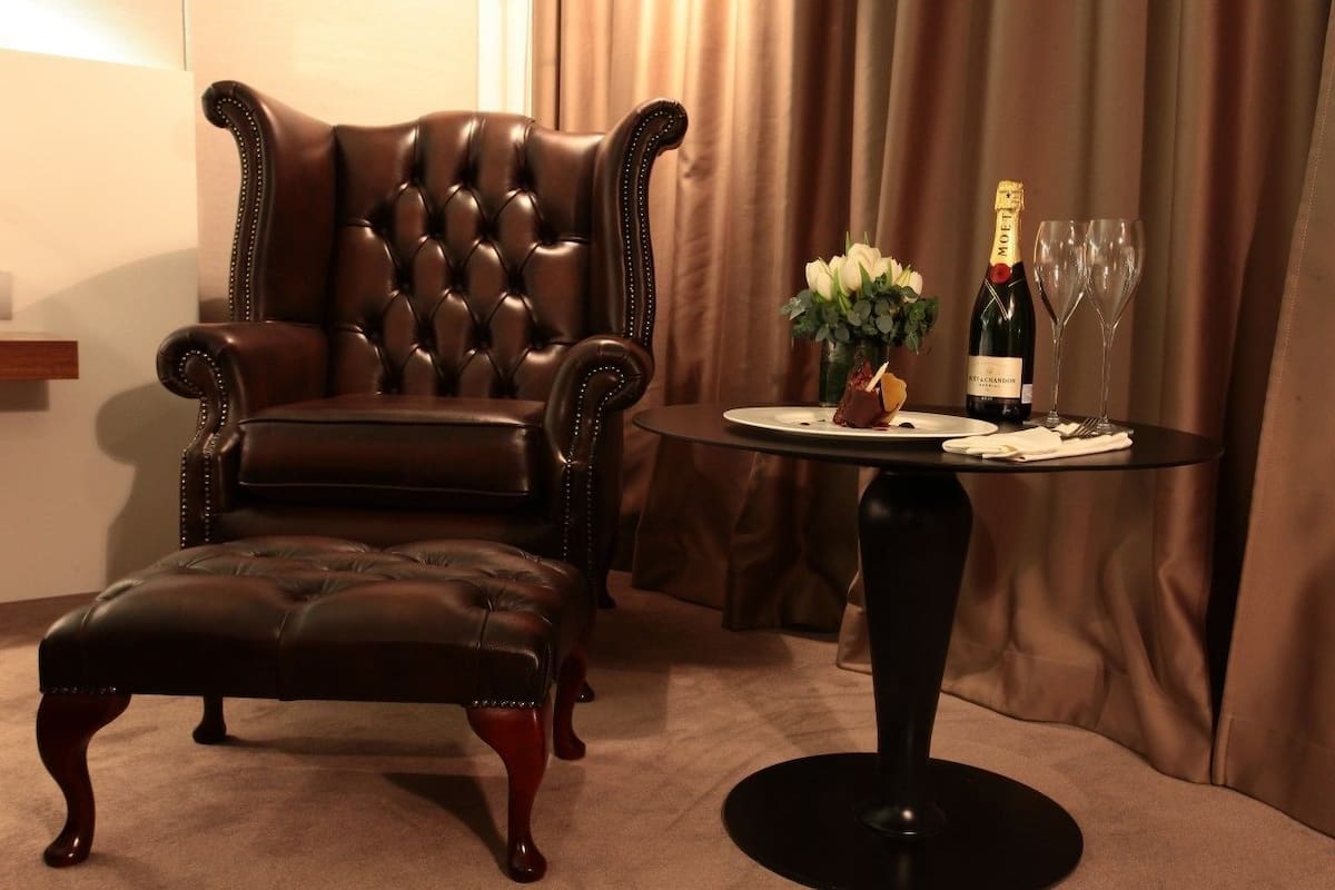 A leather armchair, ottoman, and a table with a bottle and glasses.