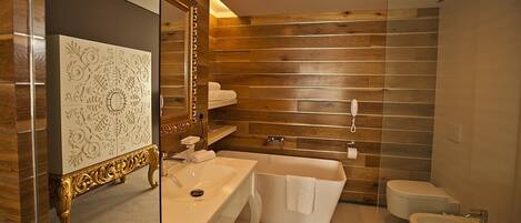 Un baño moderno con pared de madera, una bañera independiente, un tocador con espejo y un inodoro.
