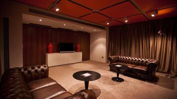 A modern living room with a leather sofa, a small round table, and a television on a wooden cabinet.