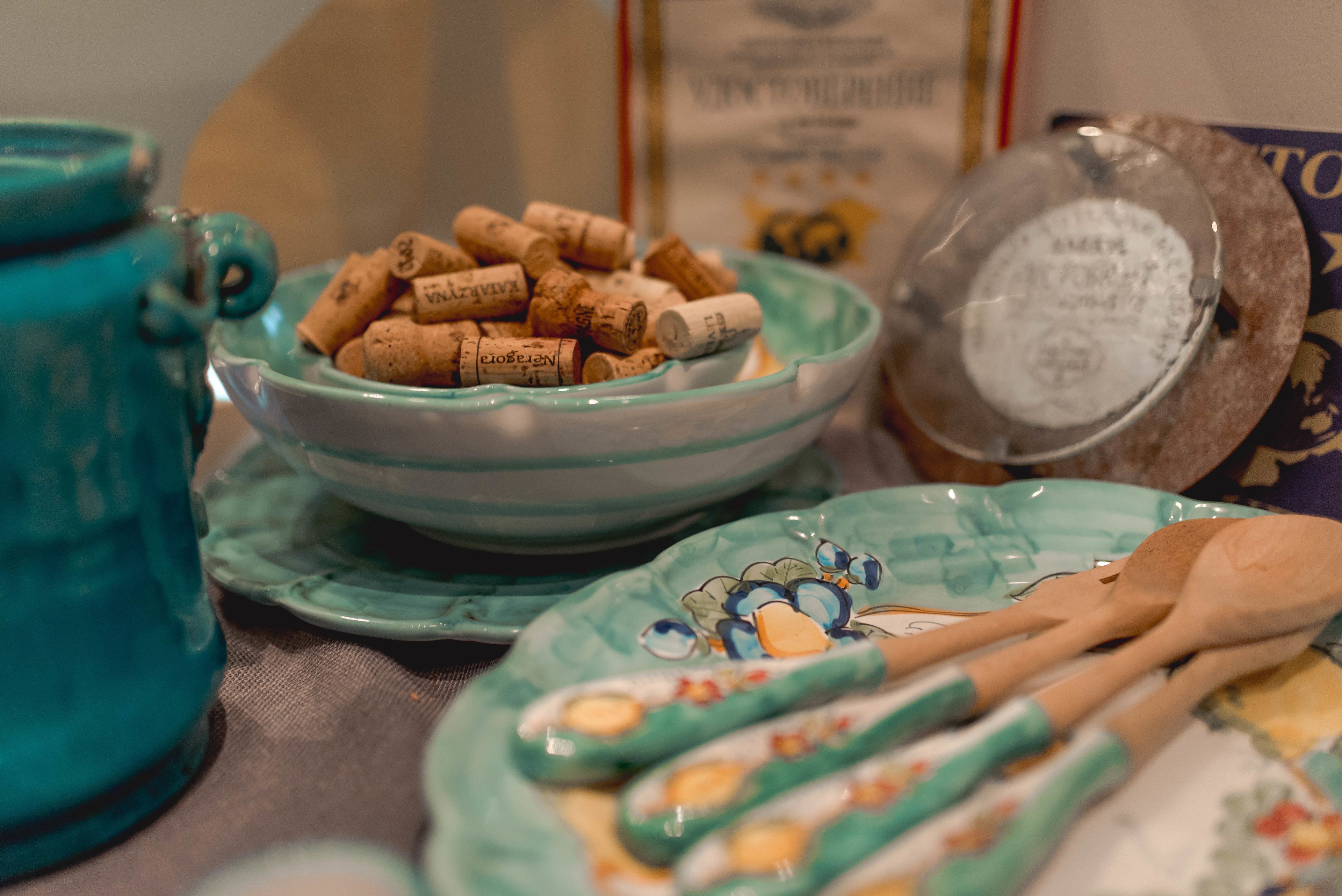 Une table sur laquelle se trouvent une théière turquoise, un bol rempli de bouchons de liège, une assiette avec une cuillère et une boîte décorative.