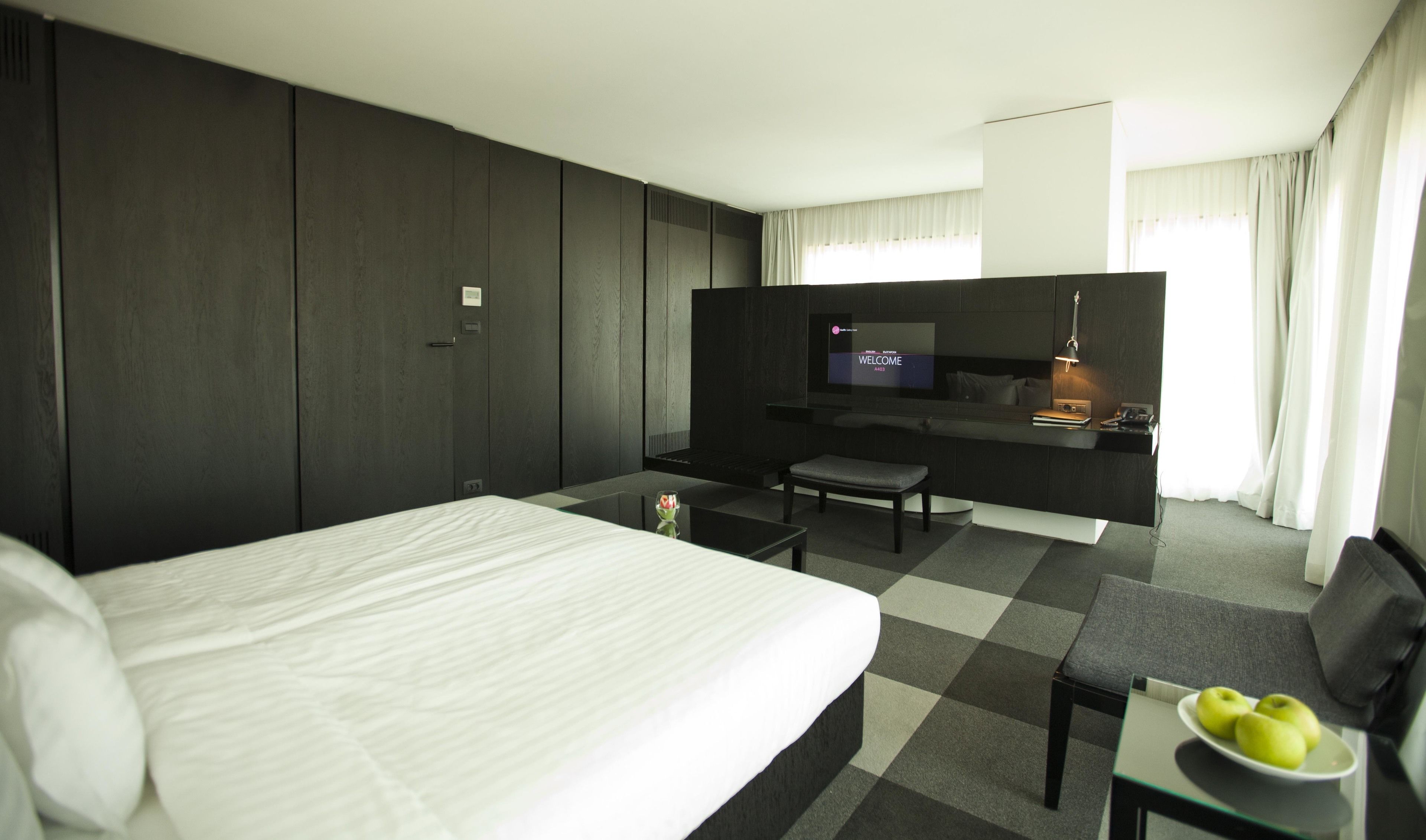 Una habitación de hotel con una cama grande, un escritorio, un televisor y una mesita con manzanas.