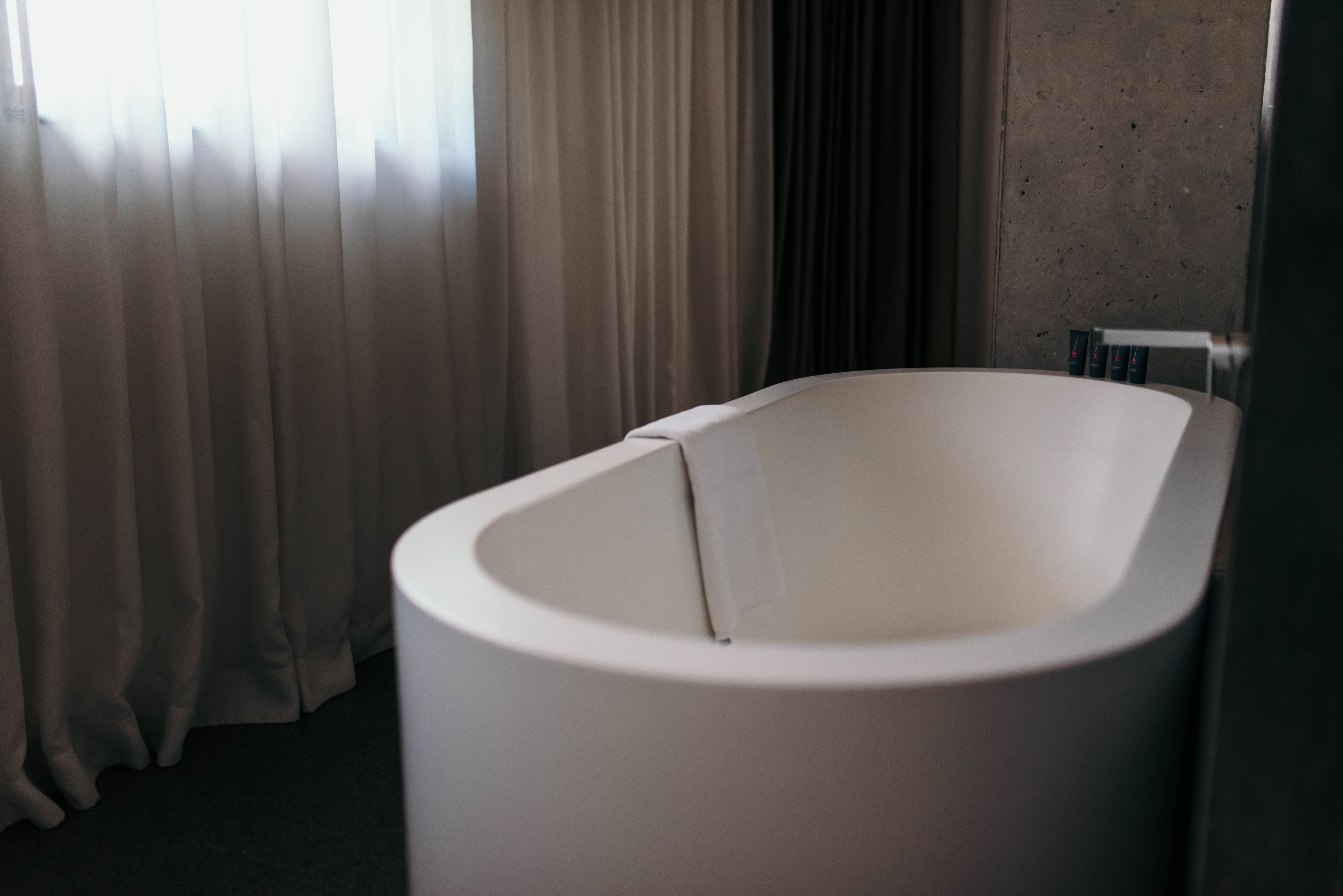 A modern bathroom with a freestanding bathtub, a shower area, and a towel rack.