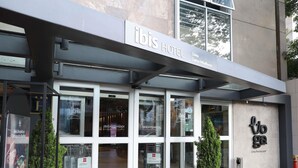 Exterior del hotel ibis con un diseño moderno, amplias ventanas de vidrio y una entrada visible.