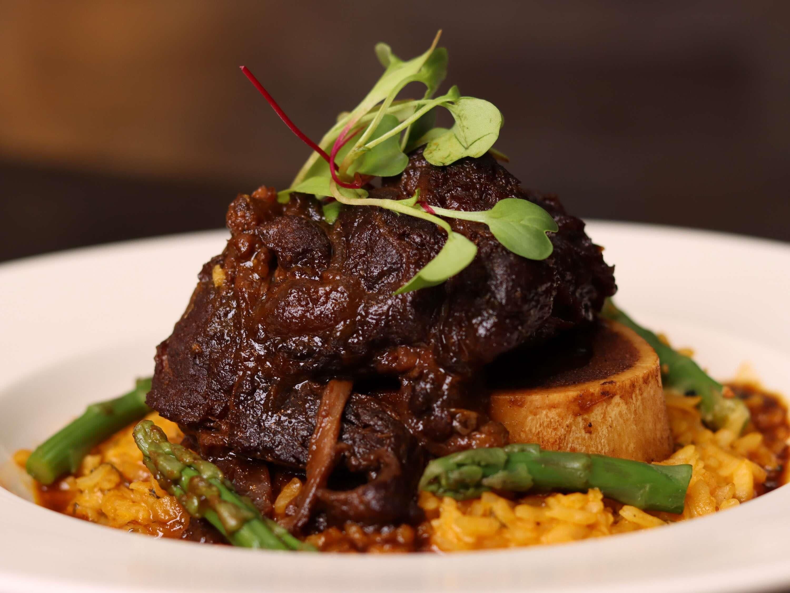 Un plato con carne, espárragos y arroz.