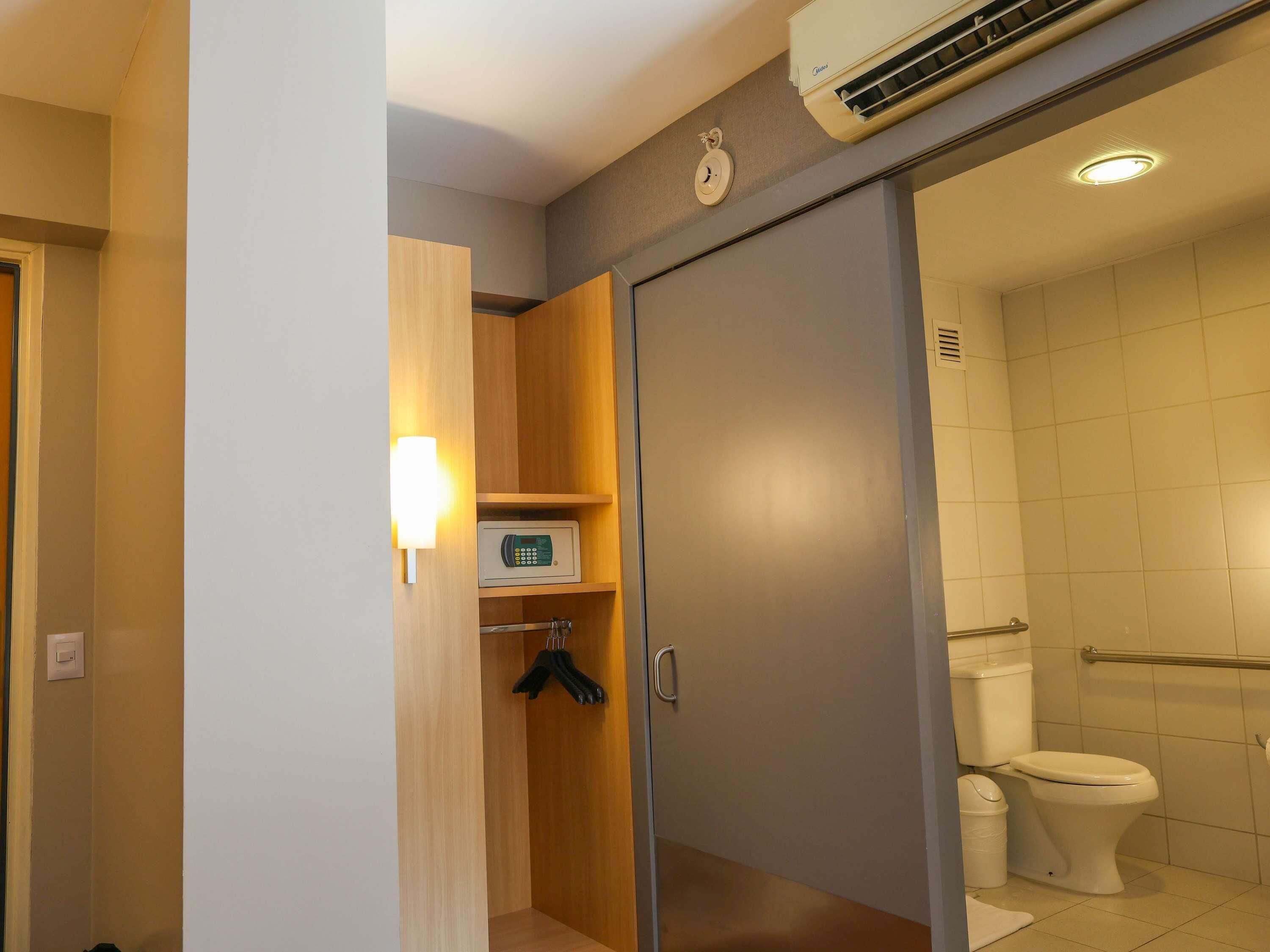 A bathroom with a toilet, a shower area, and a wall-mounted air conditioning unit.