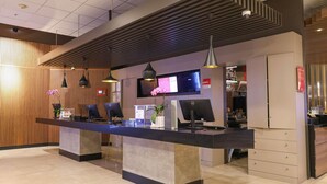 Una recepción con computadoras, un televisor y una zona de bar con botellas.