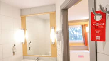 Ein Hotelbad mit Waschbecken, Spiegel und einem Schild an der Wand.