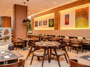 A modern restaurant interior with round tables, cushioned chairs, and a long counter. - ibis Larco Miraflores (Lima)