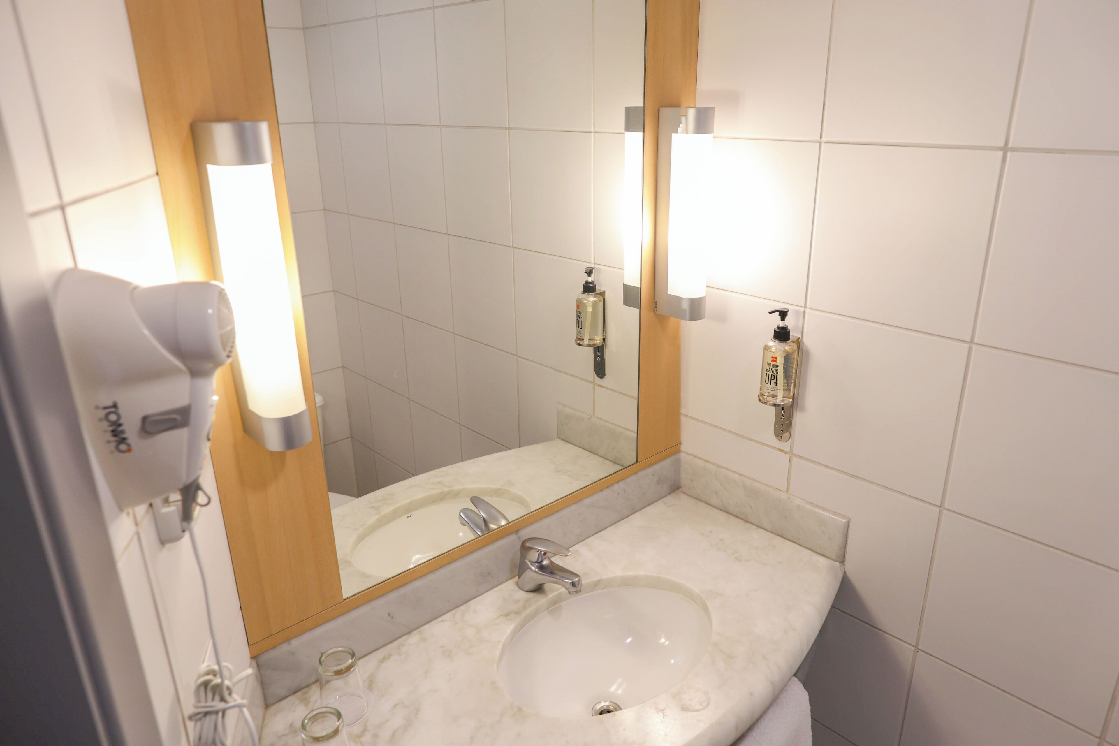 A bathroom with a sink, mirror, and hand dryer.