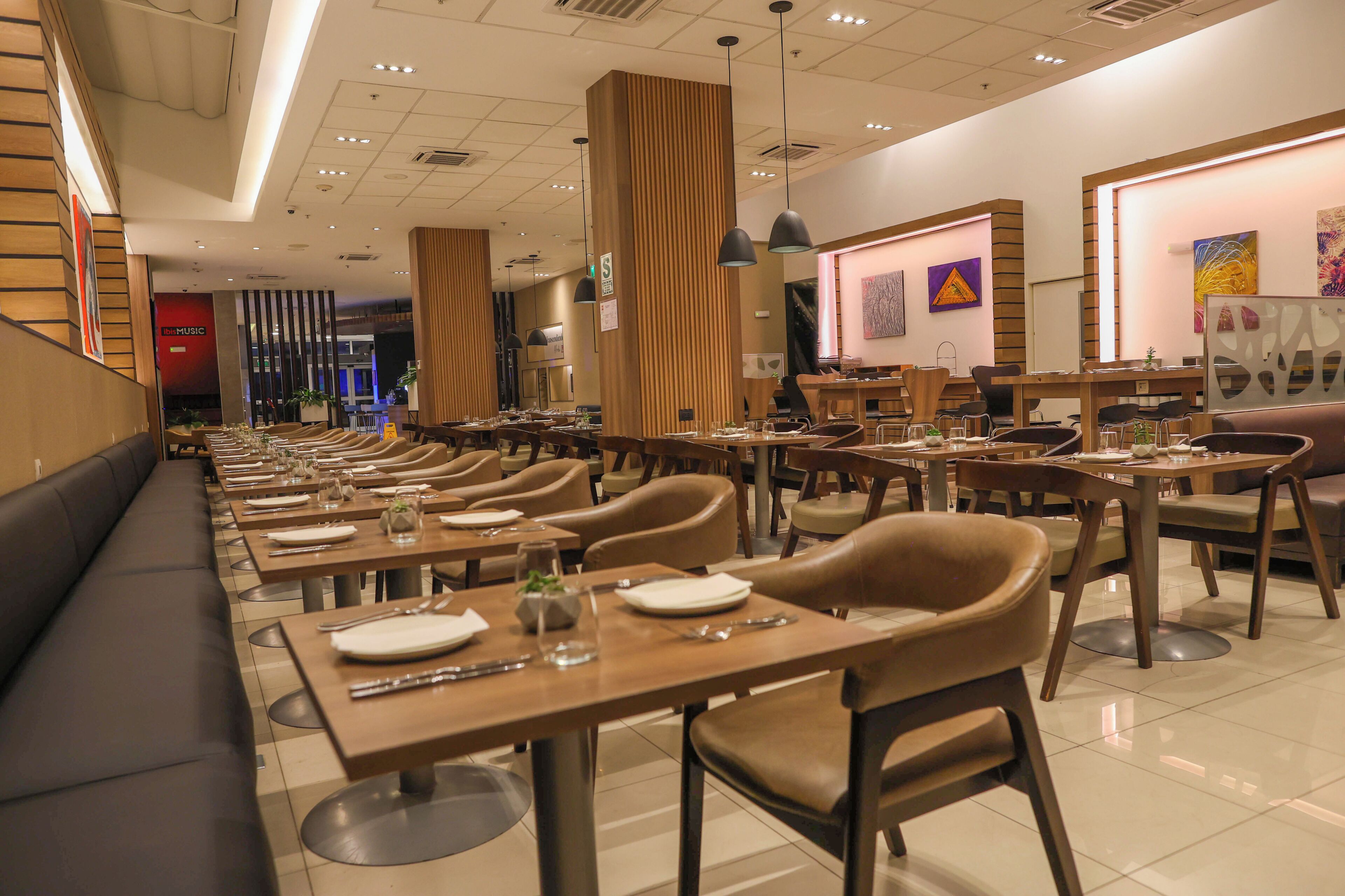 Ein modernes Restaurant mit langen Gemeinschaftstischen, gemütlichen Einzelkabinen und vielfältigen Sitzmöglichkeiten.