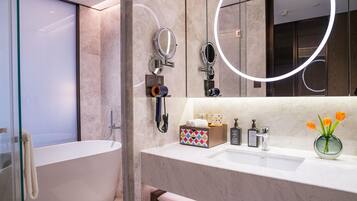 Un bagno moderno con una vasca da bagno indipendente, un mobile lavabo con specchio e un vaso con fiori.