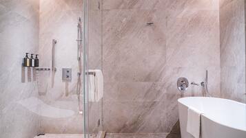 Une salle de bain moderne avec une douche à parois de verre, une baignoire sur pieds et des murs en marbre.
