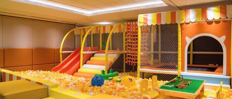 Zona de juegos infantiles con piscina de bolas, toboganes y estructuras recreativas.
