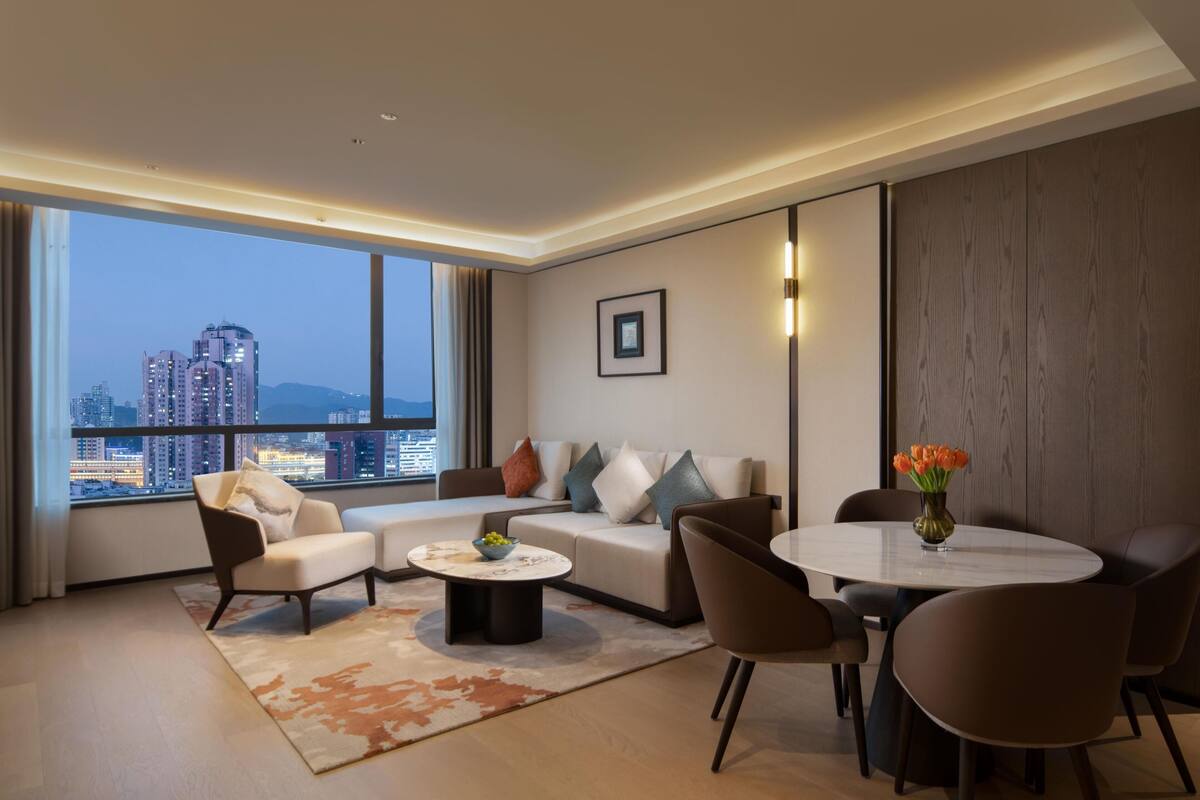 A modern living room with a sofa, chairs, a coffee table, and a dining table.