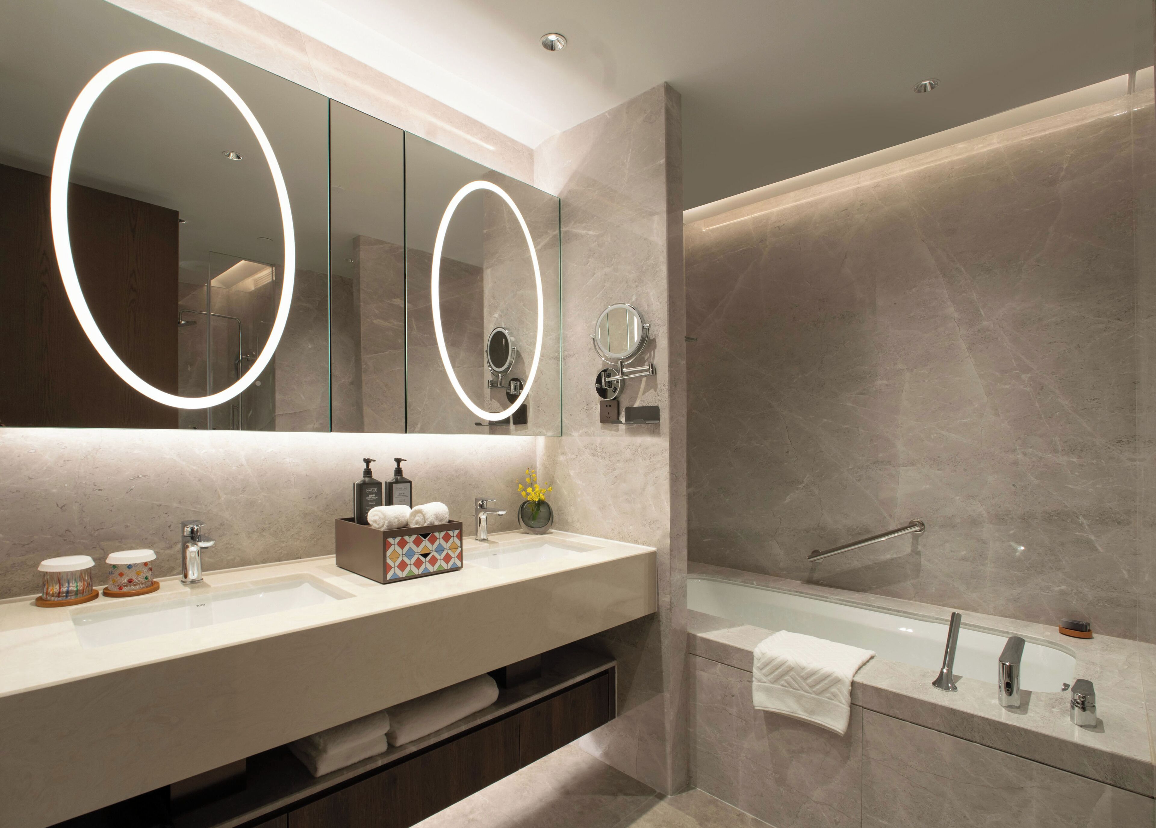 A modern bathroom with a large mirror, two sinks, and a bathtub.