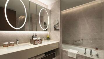 A modern bathroom with a large mirror, two sinks, and a bathtub.