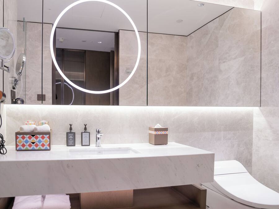 Een moderne badkamer met een grote spiegel, een wastafel en een toilet.