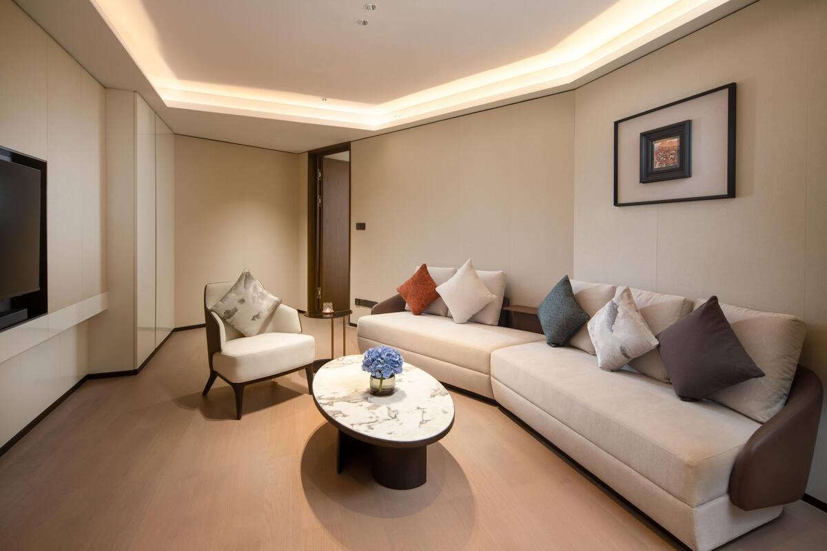 A modern living room with a sofa, armchair, and coffee table, a flat-screen TV, and a framed picture on the wall.