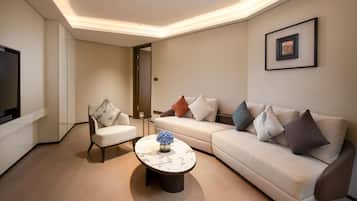 Un salon moderne avec un canapé, un fauteuil et une table basse, un téléviseur à écran plat et un tableau encadré accroché au mur.