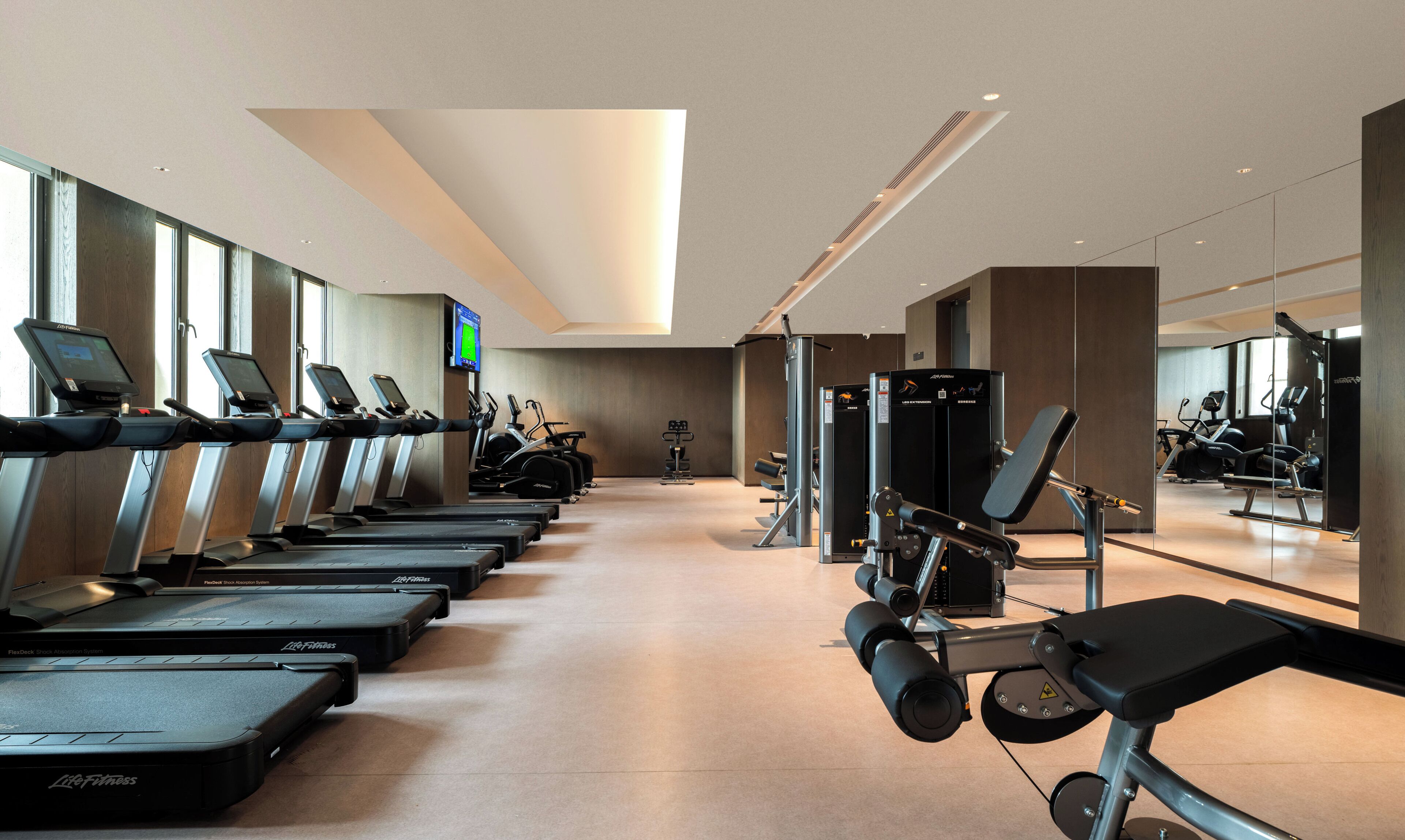 Une salle de sport équipée de tapis de course, de vélos elliptiques et de matériel de musculation.