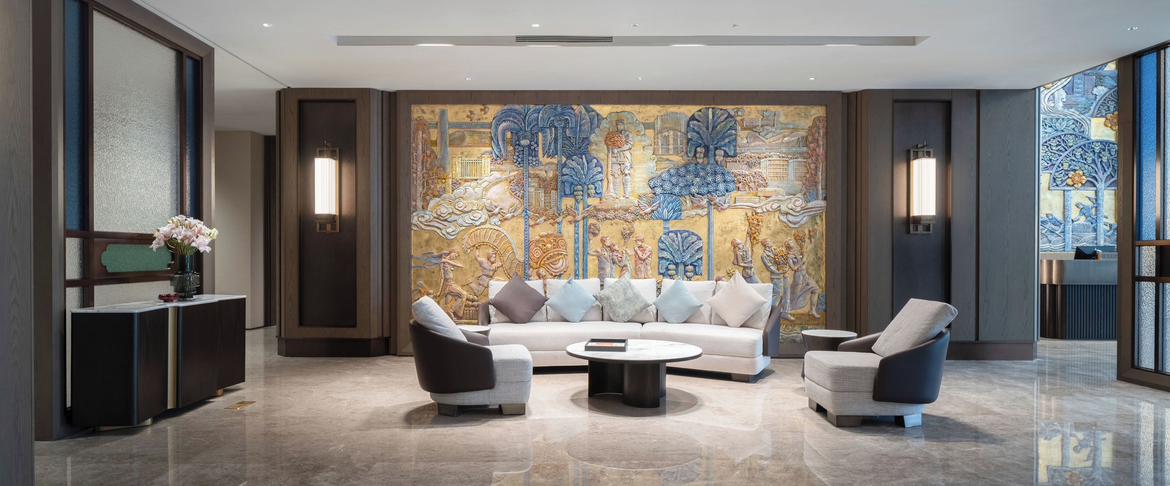Een moderne lobby met een grote muurschildering, een bank, fauteuils en een salontafel.